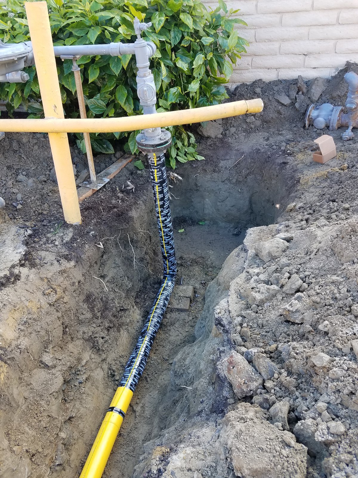 Excavated and fenced trench exposing an apartment-complex gas line repair in Orange County