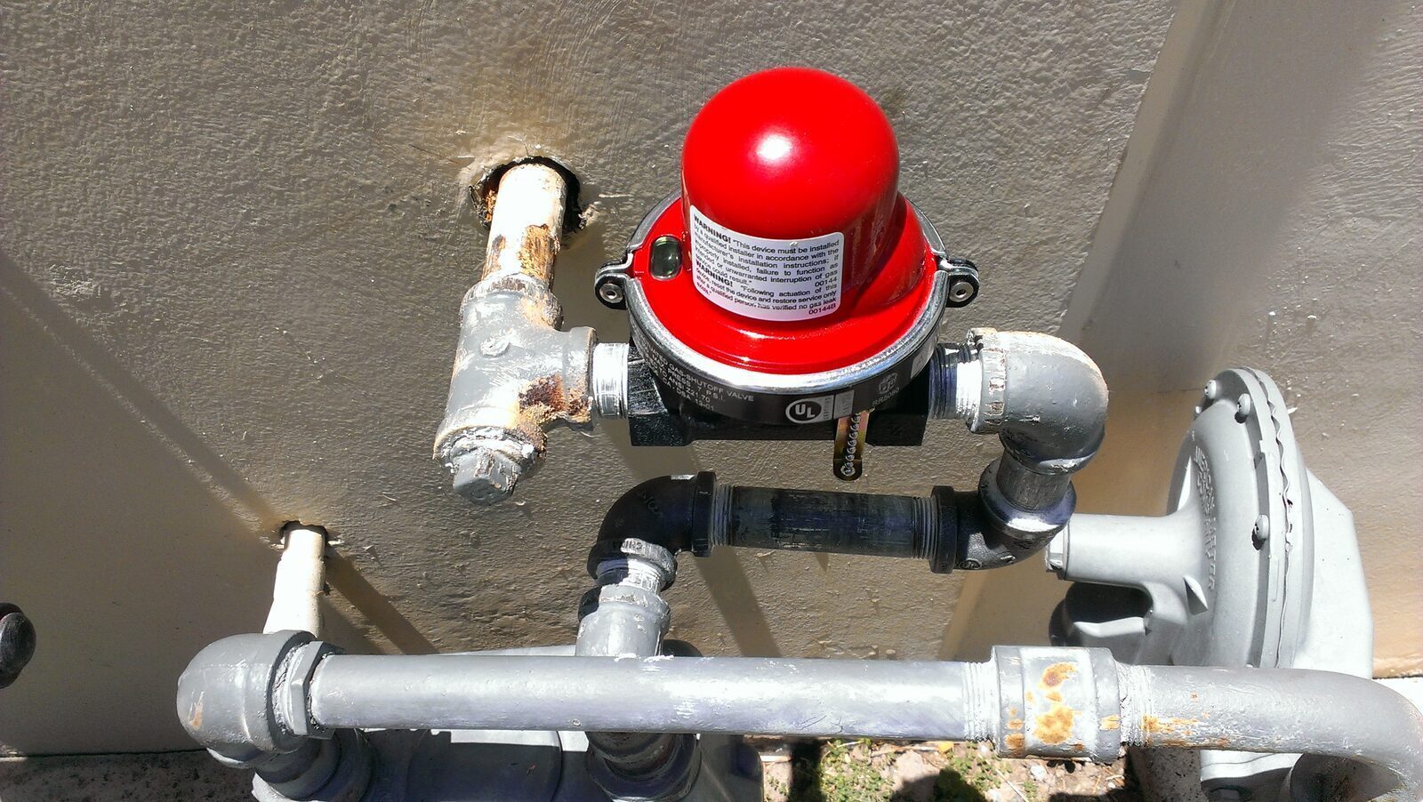 Red dome-type earthquake gas shutoff valve installed at the gas meter on an Orange County home