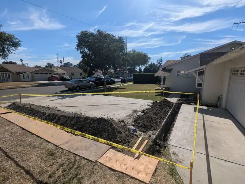 Shored and taped-off trench along the driveway on an Anaheim sewer repair job