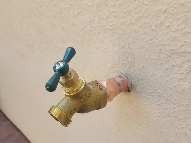 Brass hose bib on the stucco wall of an Irvine home, near where the house shutoff valve usually sits