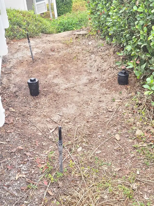 Backfilled excavation with two new sewer cleanouts at grade beside an Irvine home