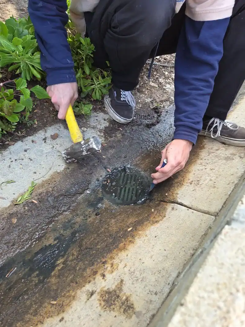 Two of our plumbers opening a backed-up drain in a Newport Beach walkway