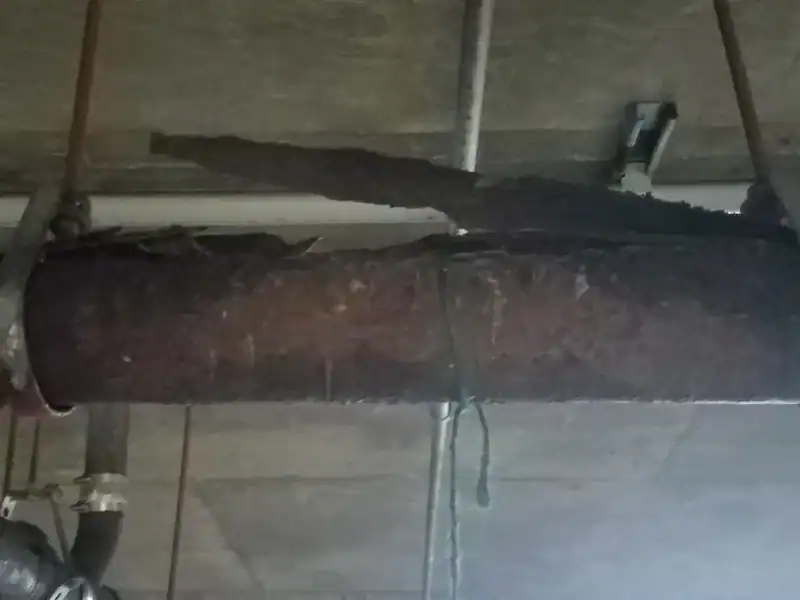 Severely rusted cast iron sewer pipe with the corrosion scale separating from the pipe wall